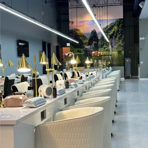 Row of clean white manicure stations with gold lamps inside Luxo Nail Spa