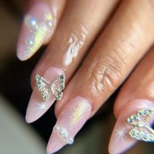 Pink shimmer almond acrylic nails decorated with crystal butterfly charms and pearls