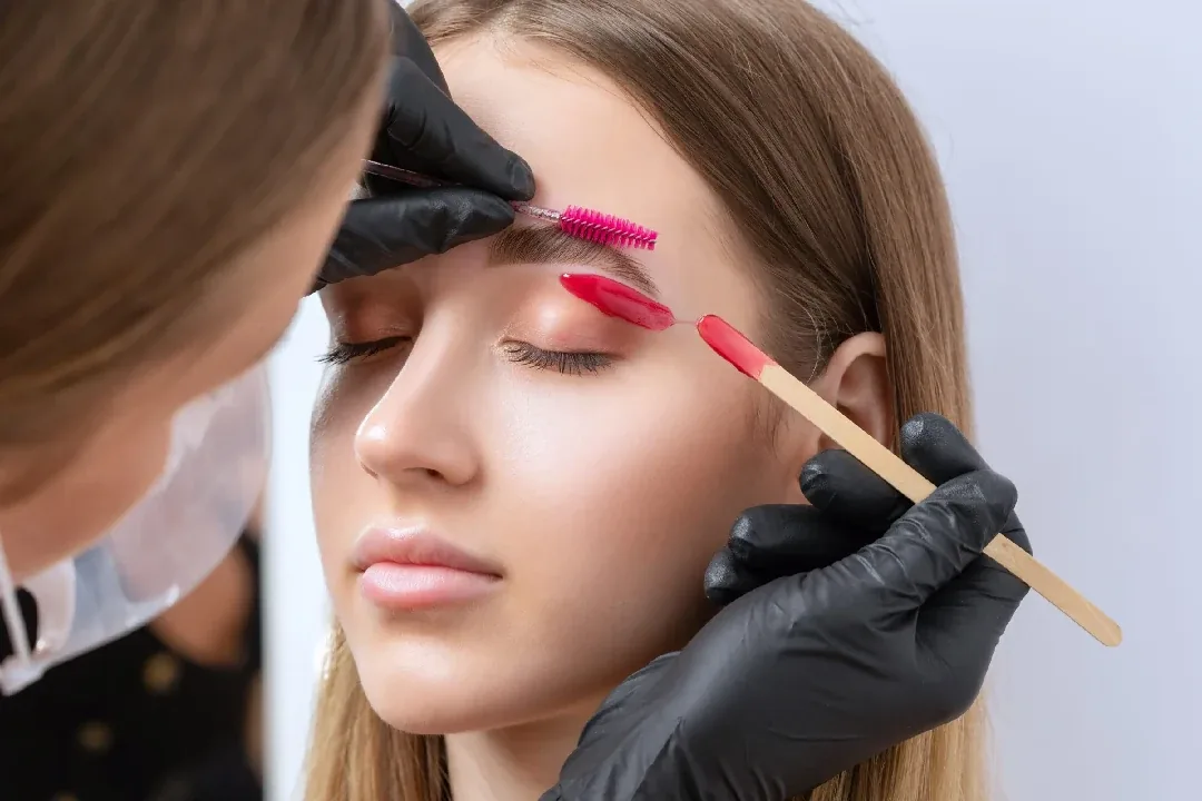 Esthetician shaping and tinting a client's brows