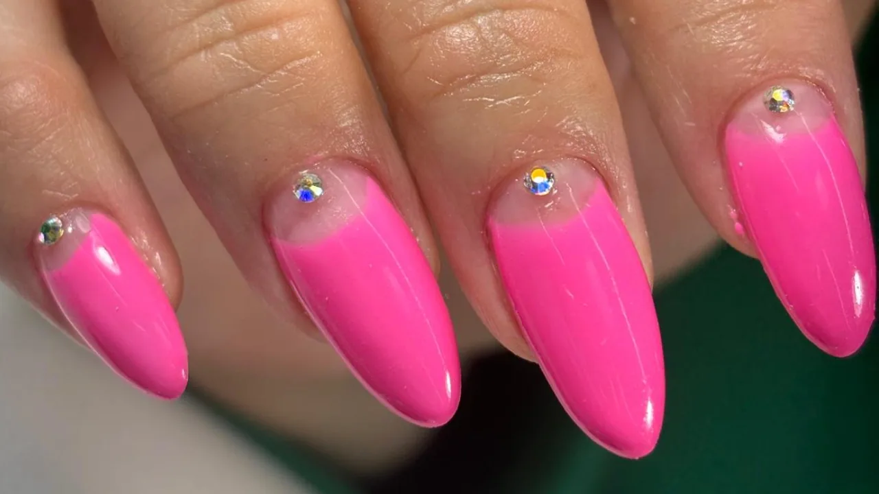 Hot pink almond nails with a single rhinestone